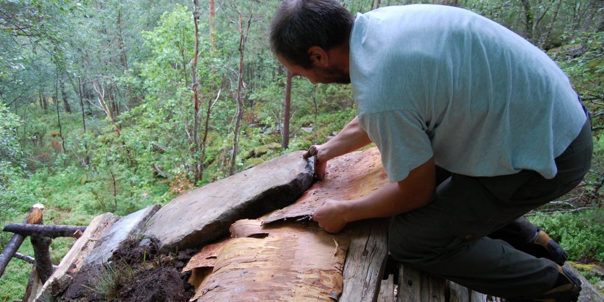 Håndverker Trond Oalann legger velessesteiner ytterst på takflata mot gavlene på Jedlaløo. (Foto: Kulturminnefondet)