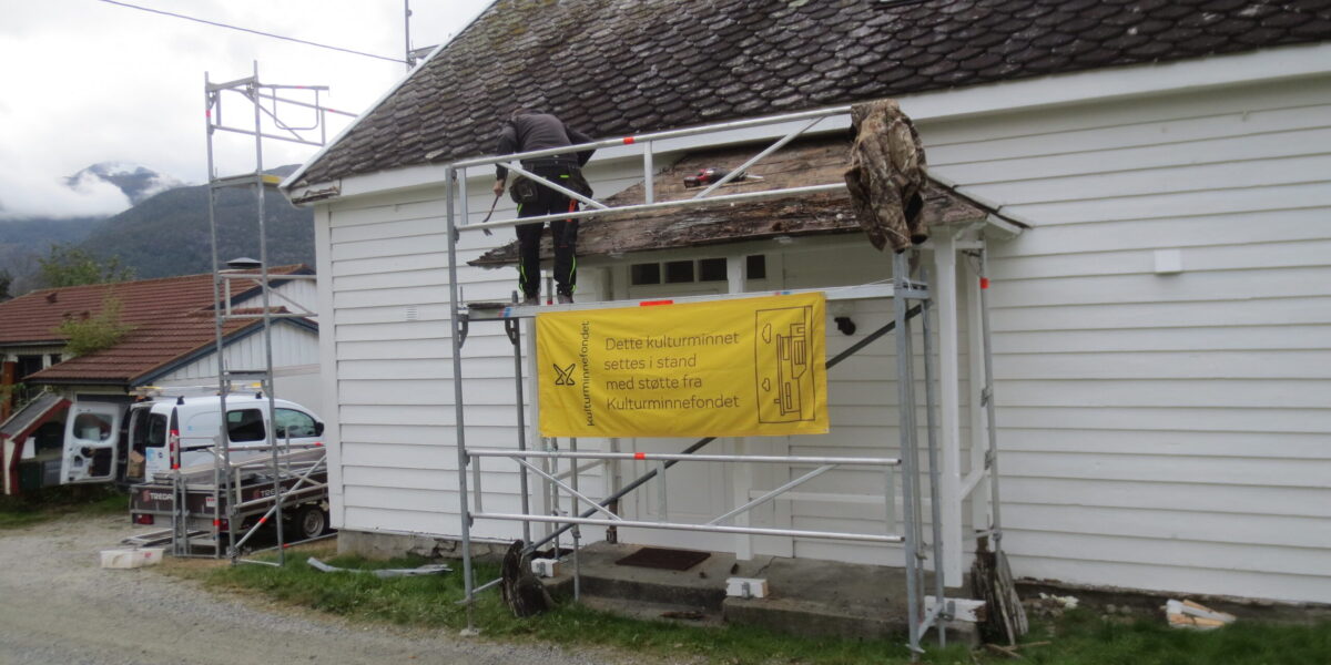 Fotoet viser arbeid med tak og vindfang i 2021. Banneret til Kulturminnefondet er på plass. Foto: S. Fitje.