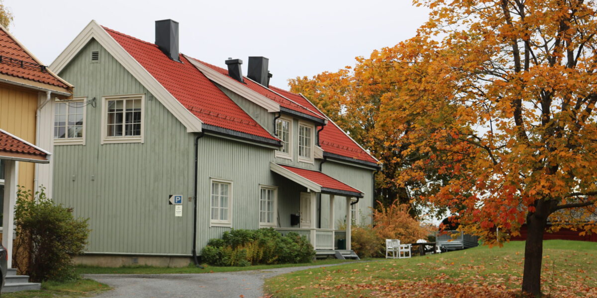 Bildet viser det grønne huset. I forkant er et tre i høstfarger.
