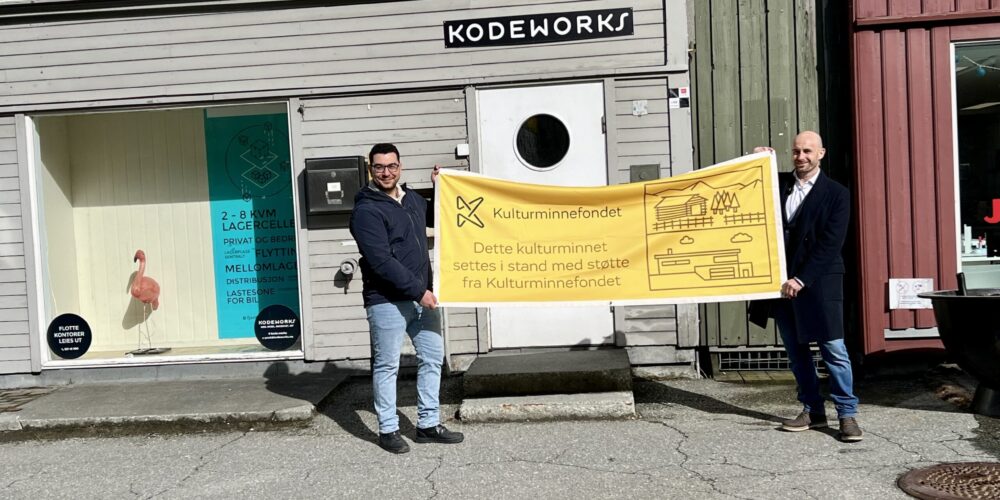 Får støtte: Kodeworks Eiendom har store planer for tømmerbrygga. Styremedlem Jetmir Rastaj overrakk det synlige beviset for støtten til Eirik Larsen i KodeWorks eiendom. Foto: Pia Wigtil